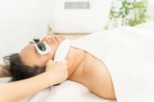 男性が目元を保護され横になり顔に機器を当てられて丁寧に施術を受けている様子